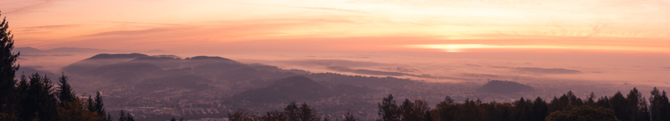 Panorama of Graz city covered if fog on autumn morning during sunraise.