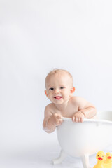 happy baby bathes in white bathtub with rubber duckies