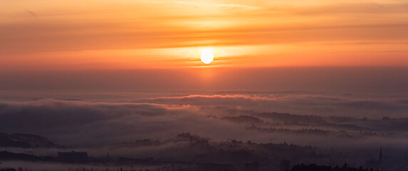 Panorama of Graz city covered if fog on autumn morning during sunraise.