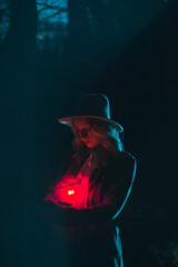 Young woman with hat holding red lantern at night