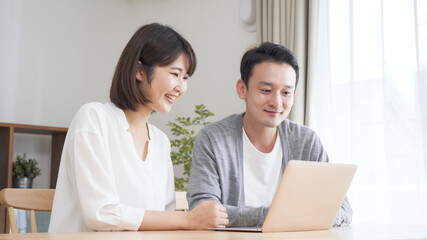 Obraz premium リビングでパソコンを見る夫婦・カップル