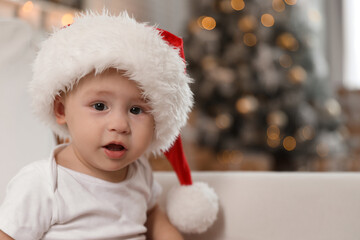 Cute little baby wearing Santa hat at home. Christmas celebration