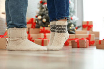 Couple in warm socks in room decorated for Christmas, closeup