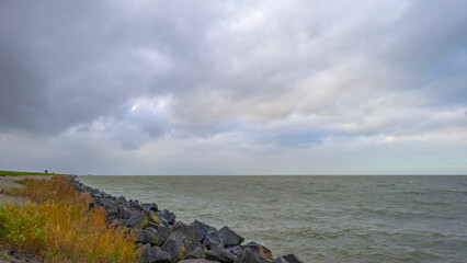 Dike under dark grey rain clouds in a stormy autumn, Almere, Flevoland, The Netherlands, November 2, 2020
