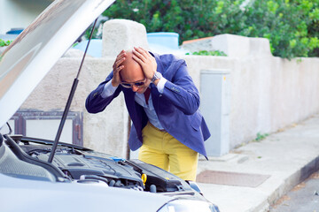 stressed man with broken car looking at failed engine