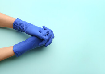 Person in medical gloves on light blue background, top view. Space for text