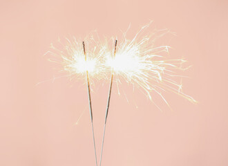 Bright burning sparklers on pink background, closeup