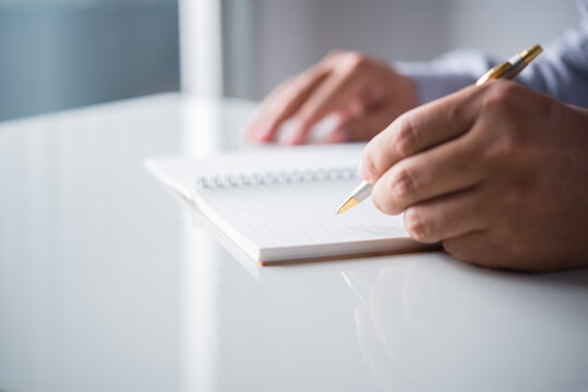 man hand holding a pen write  notes on the book