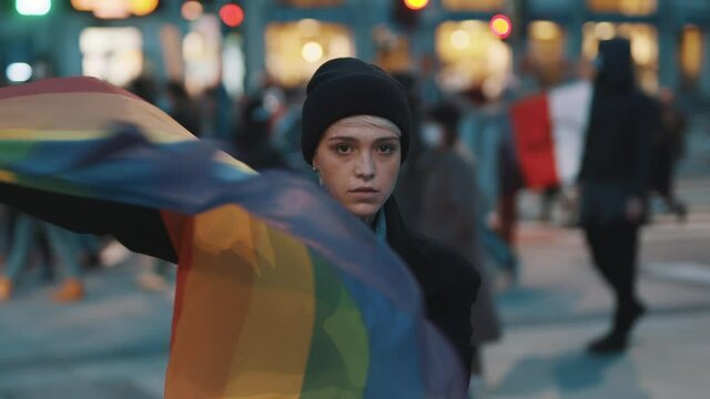 Young woman on the protest waving rainbow flag. Demonstrations during covid-19 outbreak and demand for equal rights. High quality 4k footage