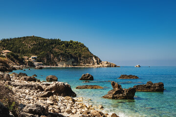 Fototapeta na wymiar Idyllic summer sunny day on rocky Greek beach with beautiful turquoise sea water, panoramic landscape nature scenery in Lefkada island, Greece