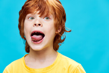 portrait of a red-haired boy sticking out tongue grimaces 