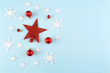 Christmas composition. Snowflakes, red decorations on blue background. Christmas, winter, new year concept. Minimal style. Flat lay, top view, copy space.