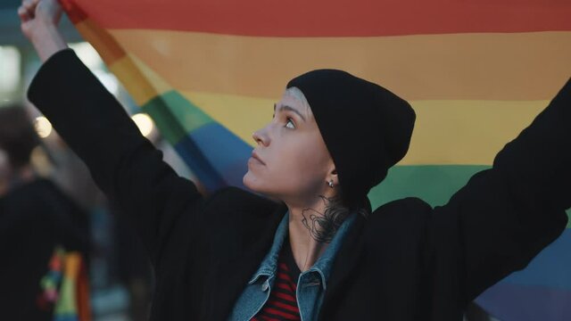 Young woman with rainbow flag. Concept of fight for sexual orientation acceptance. High quality 4k footage