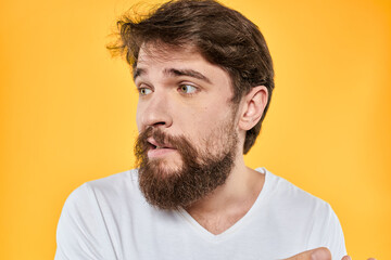 Obraz premium Man with emotional expression white t-shirt close-up studio yellow background