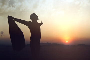 Silhouette of businessman raised hands and praying to god