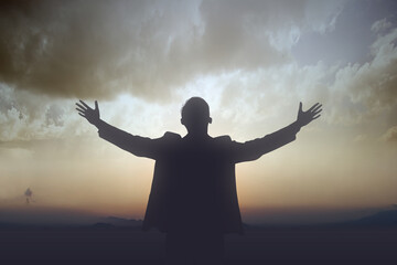 Fototapeta na wymiar Silhouette of businessman raised hands and praying to god