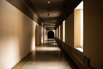 Long couloir avec des fenêtres à droite et un long mur beige à gauche