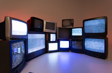 Télévisions une par dessus l'autre sur un plancher blanc avec un peu de réflection