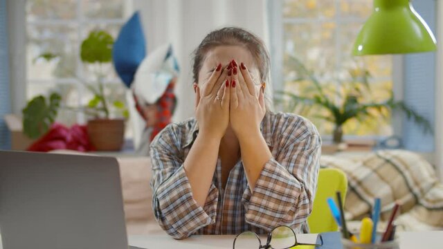 Tired Mother With Stress Working On Laptop At Home With Noisy Children On Background