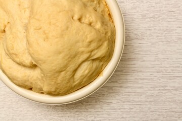 Live yellow dough in a bowl. The final fermentation process.