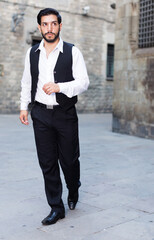 Handsome bearded man walking along old town street