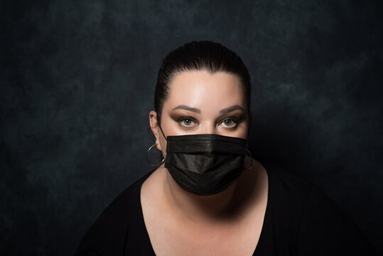 beautiful overweight woman in black medical mask on black background
