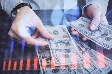 Multi exposure of financial graph drawing hologram and USA dollars bills and man hands. Analysis concept.