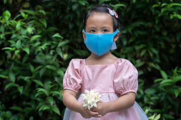 Close up Cute Girl wearing healthy face mask holding blossom fragrance millingtonia hortensis flower outdoor.