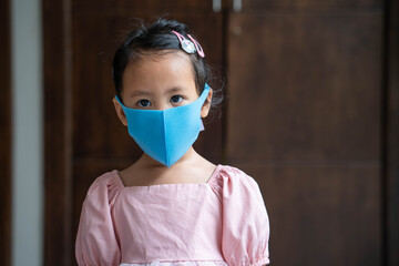 Close up Cute little girl wearing healthy face mask to prevent virus and pm2.5 standing indoor.