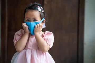 Close up Cute little girl wearing healthy face mask to prevent virus and pm2.5 standing indoor.