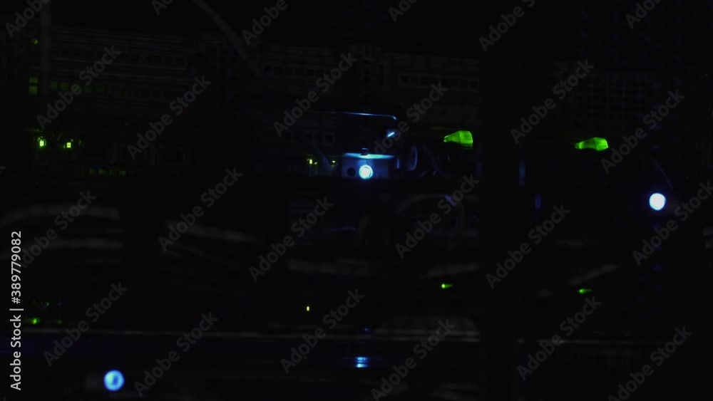 Poster flashlight of thief shining on a data server rack. concept of cyberwar, hacking. close shot