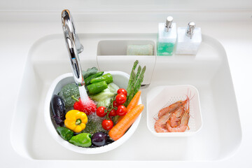 シンクで洗う野菜とエビ