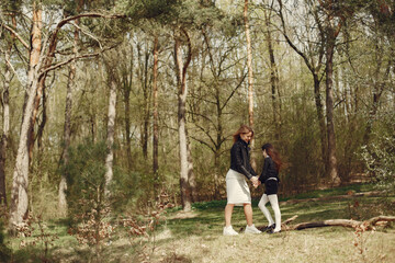 Beautiful family in a park. Woman in a white dress and jacket. Mother with daughter.