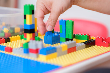 Hand picked jigsaw puzzle plastic building blocks on toy table.