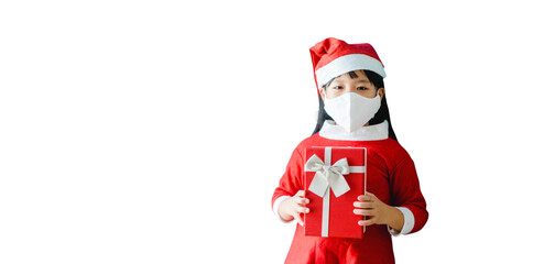 Christmas during coronavirus covid19.Little asian girl wearing mask holding gift box isolated on white banner.Christmas winter celebration at home.New normal, Social distancing, Christmas present.