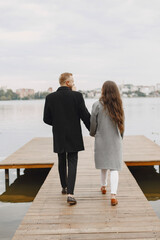 Cute couple in a park. Lady in a gray coat. People on the pier.