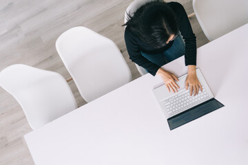 Top-down image of young woman using laptop in the office
