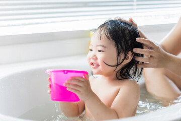 Cute Asian kid toddler having a bath cleaning bathing bath tub with mother, parenthood child hood...