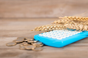 A calculator with ripe wheat ears on it and a pile of euro coins next to it