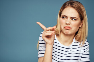 woman wearing striped t-shirt cropped view blue isolated background displeased facial expression