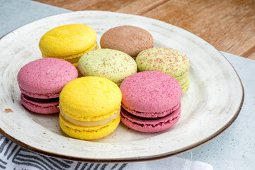 Fototapeta na wymiar Multicolored macarons on a plate and wooden background