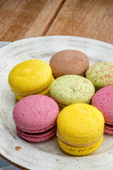 Multicolored macarons on a plate and wooden background