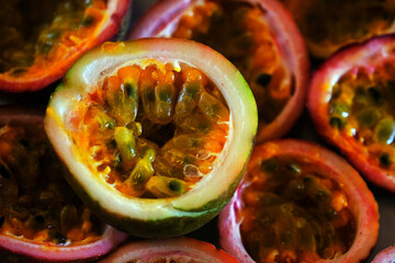 A half cut passion fruit with blurred passion fruits background. Fresh organic fruit.