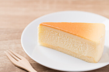 Sliced of vanilla cheesecake on white plate with fork