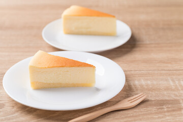 Sliced of vanilla cheesecake on white plate with fork
