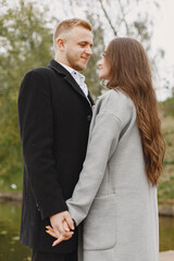 Fototapeta premium Cute couple in a park. Lady in a gray coat. People on the pier.