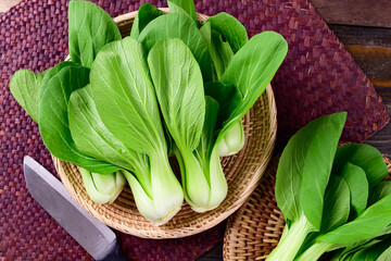 Fresh Bok Choy or Pak Choi (Chinese cabbage) in bamboo basket on wooden background, Organic vegetables, Top view
