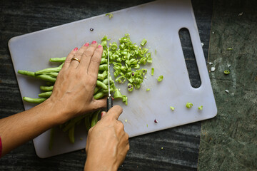 Woman Hand cutting chopping Organic Beans or French beans vegetables from home kitchen garden farm...