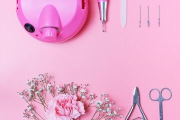 Manicure tools and drill on pink background with copy space.