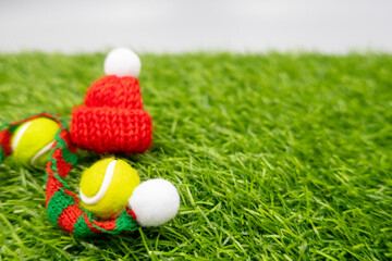 Naklejka premium Tennis Christmas Holiday with tennis ball and Santa hat on green grass